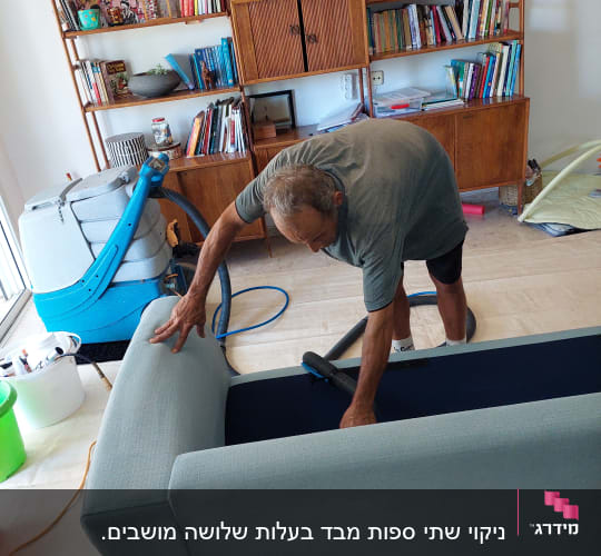 אדם מנקה ספה עם שואב אבק כחול